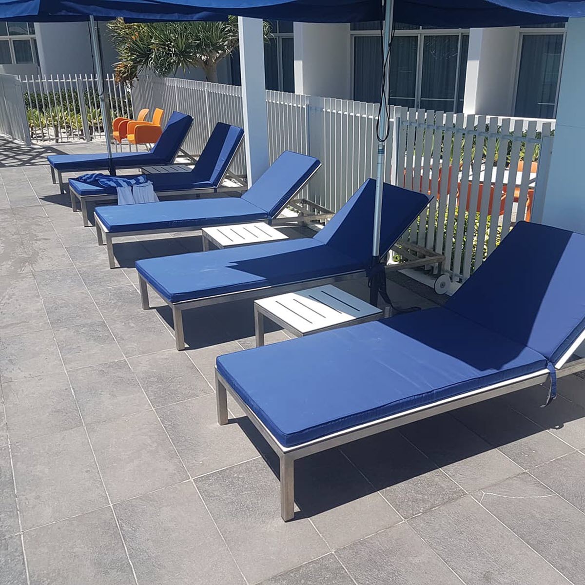 Plain blue patio cushions in line showcased in an Australian backyard pool.